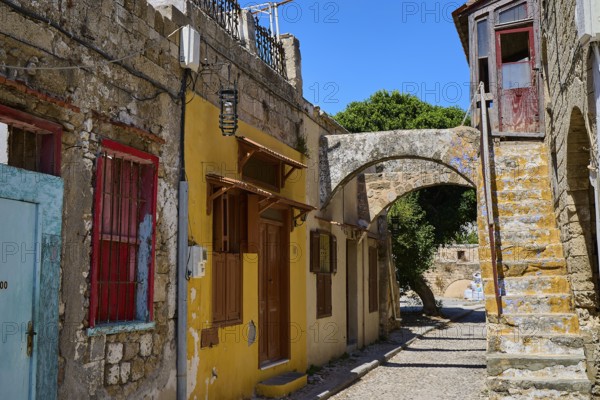 Narrow alley with old houses, yellow facades and colourful windows, Jewish Quarter, Rhodes Old Town, Rhodes Town, Rhodes, Dodecanese, Greek Islands, Greece