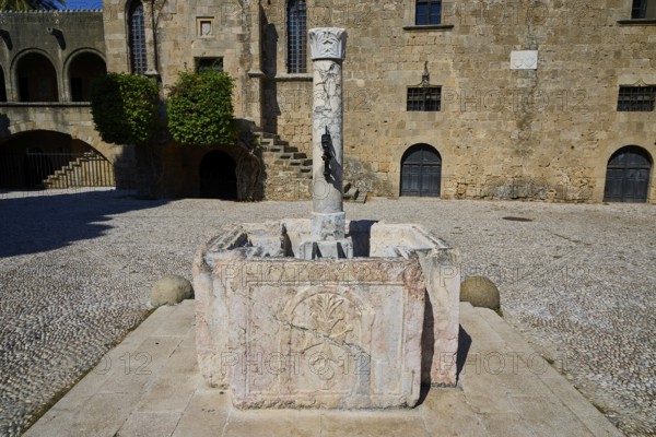 Medieval sandstone fountain with stone column in a historic ruin in the sunshine, Rhodes Old Town, Rhodes Town, Rhodes, Dodecanese, Greek Islands, Greece