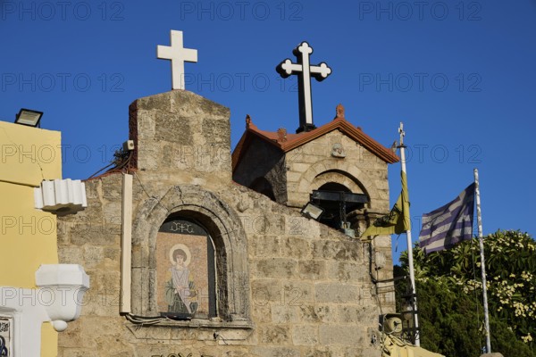Church of Agios Panteleimon, stone church with crosses and flags in the background under a blue sky, Rhodes Old Town, Rhodes Town, Rhodes, Dodecanese, Greek Islands, Greece