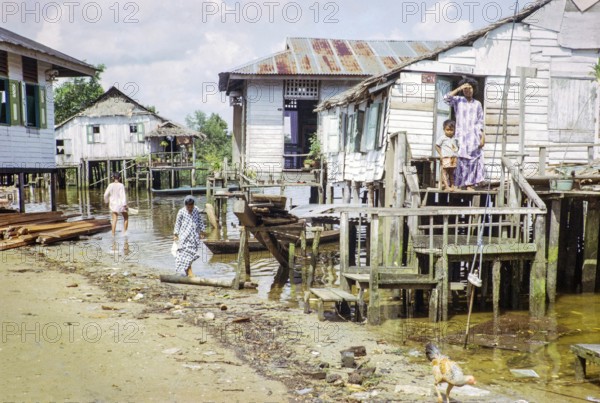 Houses on stilts above sea water in coastal village of Kampong Lorong Fatimah in Singapore, Southeast Asia c 1964