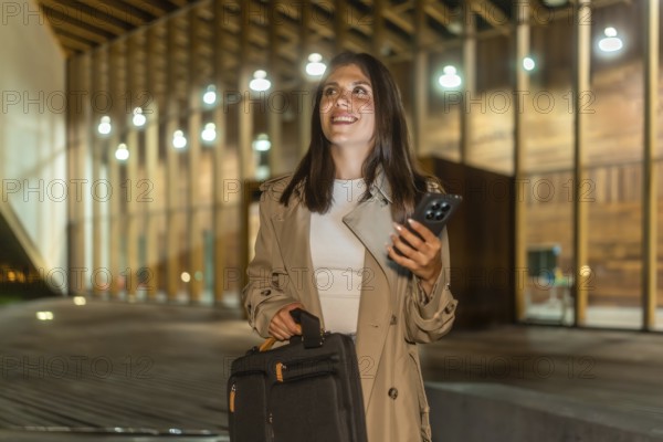 Young businesswoman walking confidently at night in an urban setting, carrying a briefcase and using a smartphone, embodying determination and modern communication in her professional journey