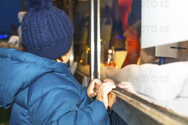 Curious child admiring a festive christmas window display in bayonne, france, during the magical holiday season
