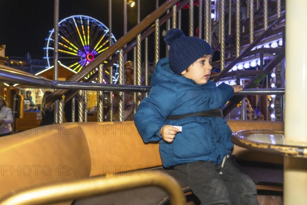 Young child enjoying a carousel ride at a vibrant christmas market in bayonne, france, creating a magical holiday experience
