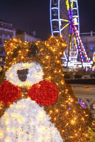 Festive christmas bear decoration shines brightly in bayonne, france, with a ferris wheel adding to the enchanting christmas atmosphere