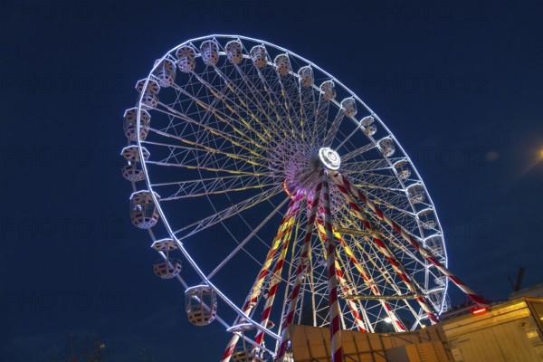 Ferris wheel illuminating the night sky during christmas festivities in bayonne, france, creating a festive and magical atmosphere
