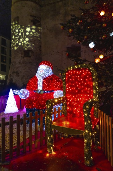Luminous santa claus installation sitting on his throne during christmas festivities in bayonne, france