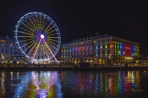 Colorful ferris wheel and city hall reflecting in the river nive in bayonne, france, during christmas night