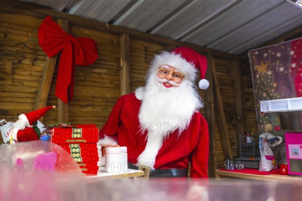 Santa claus impersonator preparing christmas gifts in a wooden kiosk at a christmas market in bayonne, france
