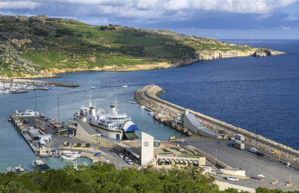 View of jetty for ferries from to Valletta island Malta and moored ferry car ferry, on the right high protective wall against strong swell waves, Mgarr, Gozo, Malta