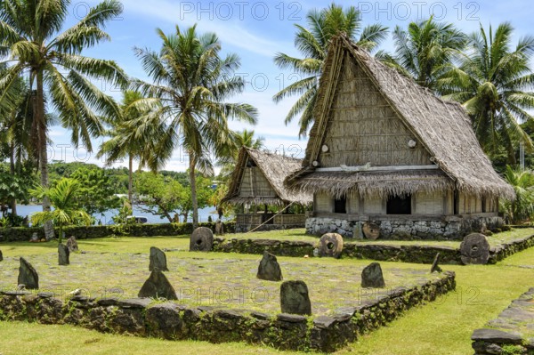 Traditional houses in museum village of Yap Island in front of dance area wonbey for traditional dances with in the centre small plateau platform malal of stone tiles and upright backrests for spectators, Yap Island, Yap State, Caroline Islands, FSM, Federated States of Micronesia, Australia, Oceania