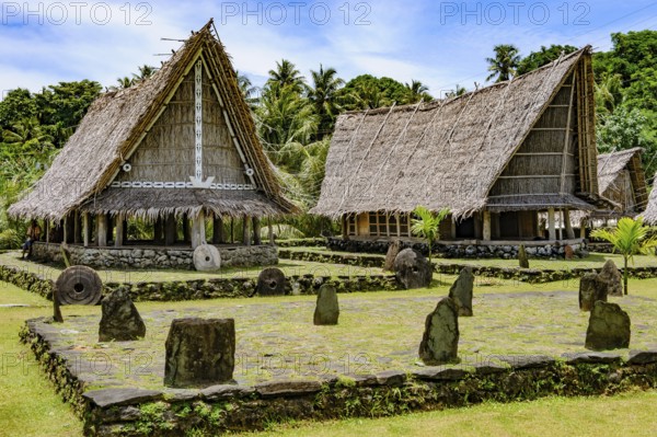 Left traditional community house right Faluw men's house Men's House meeting houses in museum village of Yap Island in front dance area wonbey for traditional dances with in the centre small plateau platform malal made of stone tiles and upright backrests for spectators, Yap Island, Yap State, Caroline Islands, FSM, Federated States of Micronesia, Australia, Oceania