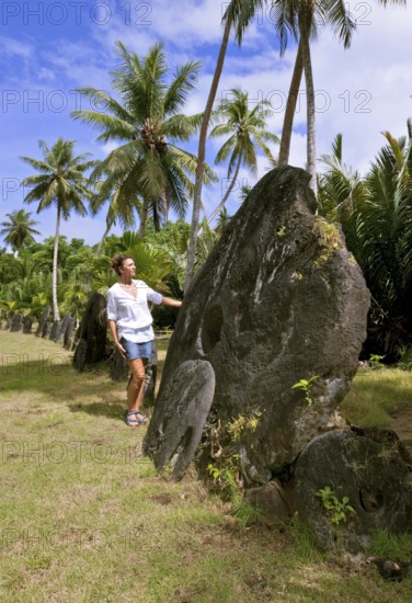 Tourist standing next to oversized huge stone coins real currency in stone money bank stone money bank in jungle of Yap Island, Yap Island, Yap State, Caroline Islands, FSM, Federated States of Micronesia, Australia, Oceania