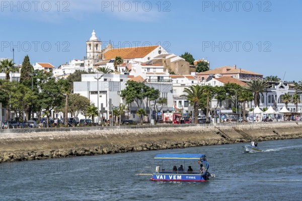The skyline of the old town of Lagos, on the river Bensafrim, harbour canal, passenger ferry across the Vai Vem Balsa canal, in the west of the Algarve, Portugal