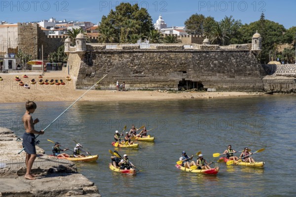 Kayak tours to the rocky coast Ponta da Piedade, groups of tourists in kayaks on the sea to the rugged coastal landscape, children fishing at the harbour, from Lagos, in the west of the Algarve, Portugal Forte Ponta da Bandeira