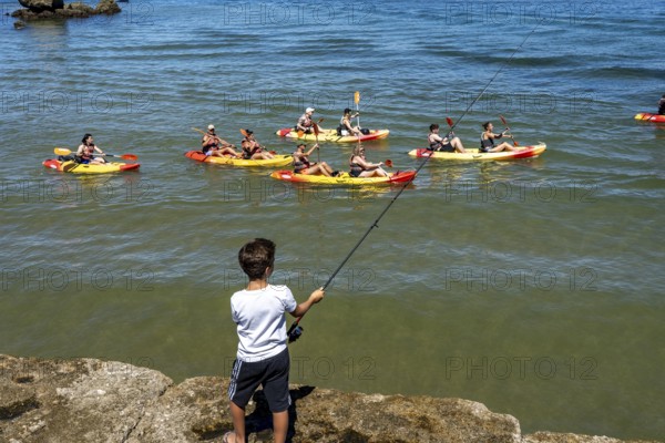Kayak tours to the rocky coast of Ponta da Piedade, groups of tourists in kayaks on the sea to the rugged coastal landscape, children fishing at the harbour, from Lagos, in the west of the Algarve, Portugal