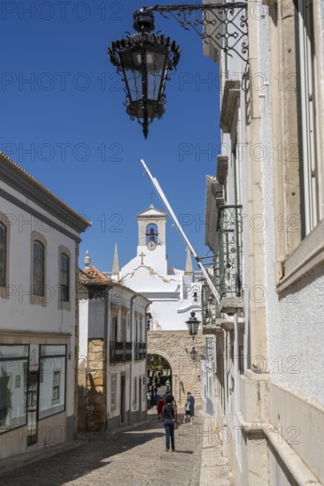 Faro, old town centre alley, R. do Municipio, view of the Arco da Vila city gate, Algarve, Portugal