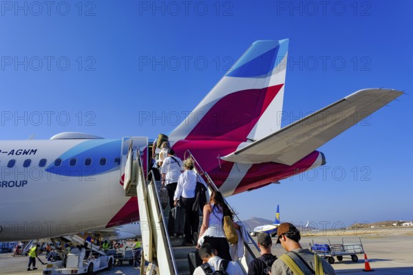 Mykonos, Greece - EUROWINGS. At Mykonos Airport, holidaymakers board a Eurowings aircraft via an external staircase on the apron. Behind them is a Ryanair aircraft