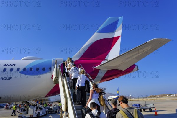 Mykonos, Greece - EUROWINGS. At Mykonos Airport, holidaymakers board a Eurowings aircraft via an external staircase on the apron. Behind them is a Ryanair aircraft