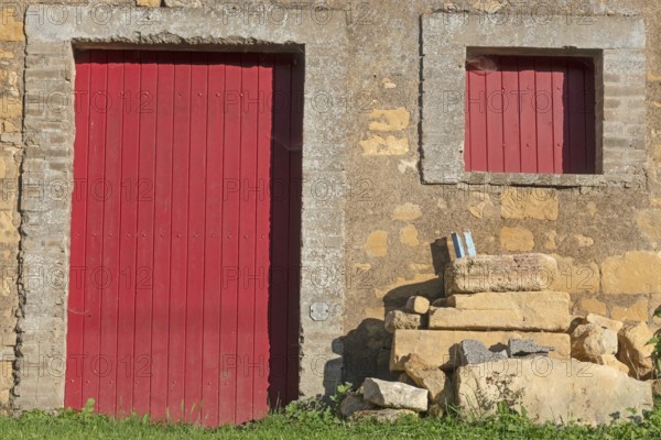Red door and windows, historic house façade, yellow sandstone, Marville, Renaissance village, Département Meuse, Grand Est, France