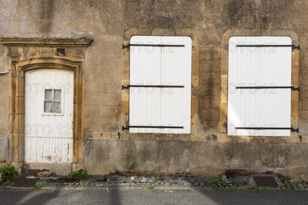Door and 2 white, closed windows made of wood, historic house facade, yellow sandstone, Marville, Renaissance village, Département Meuse, Grand Est, France