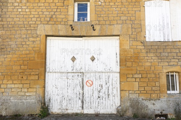 Closed white wooden door and windows, historic house façade, yellow sandstone, Marville, Renaissance village, Département Meuse, Grand Est, France