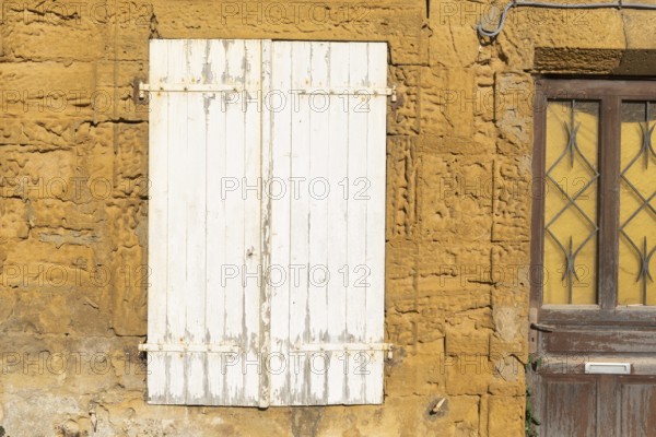 Closed door and white wooden window, historic house façade, yellow sandstone, Marville, Renaissance village, Département Meuse, Grand Est, France