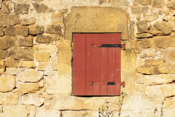 Red wooden window, historic house façade, yellow sandstone, Marville, Renaissance village, Département Meuse, Grand Est, France