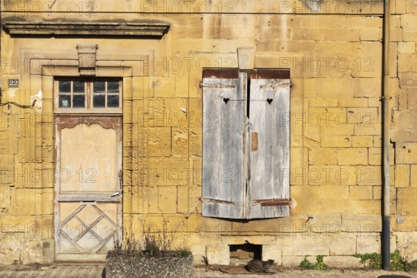 Closed wooden door and windows, historic house façade, yellow sandstone, Marville, Renaissance village, Département Meuse, Grand Est, France