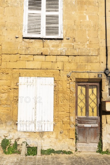 Closed door and white wooden window, historic house façade, yellow sandstone, Marville, Renaissance village, Département Meuse, Grand Est, France
