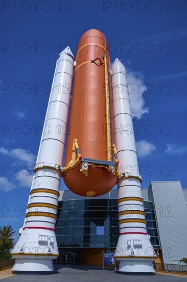Large orange space shuttle with booster rockets in front of a modern building, Kennedy Space Center Visitor Complex, Merritt Island, Florida, USA