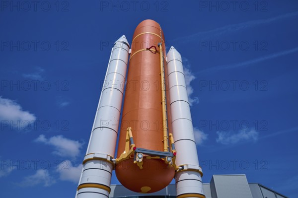 Large orange space shuttle with two launch vehicles against a blue sky, Kennedy Space Center Visitor Complex, Merritt Island, Florida, USA