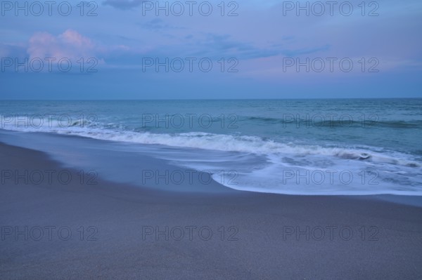 Beach at dusk with gentle waves and blue-grey sky, Cocoa Beach, Port Canaveral, Florida, USA