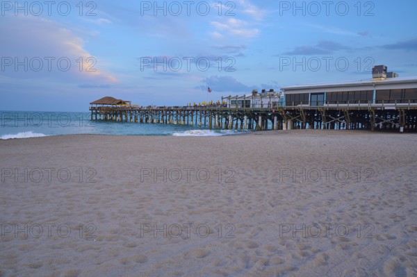 A sandy beach with a pier jutting into the blue sea under a slightly cloudy sky, Westgate Cocoa Beach Pier, Cocoa Beach, Port Canaveral, Florida, USA