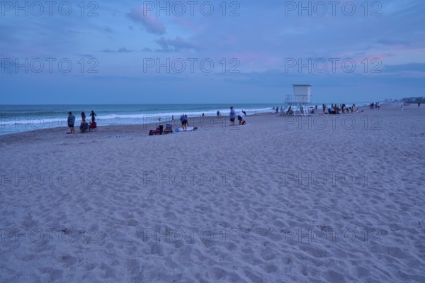 People enjoying the beach at dusk under a blue sky, Cocoa Beach, Port Canaveral, Florida, USA