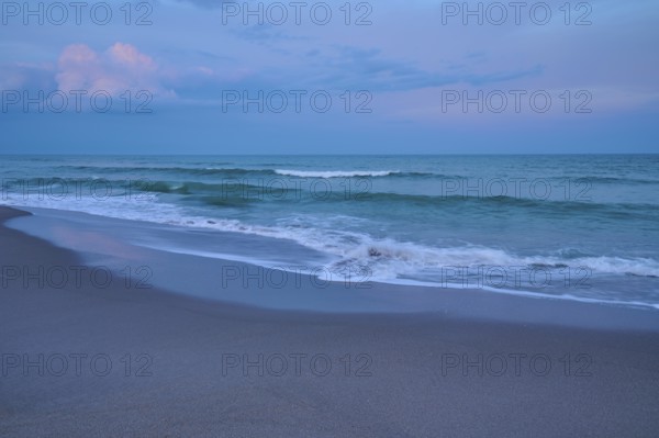 Tranquil beach landscape at dusk with gentle waves and blue sky, Cocoa Beach, Port Canaveral, Florida, USA