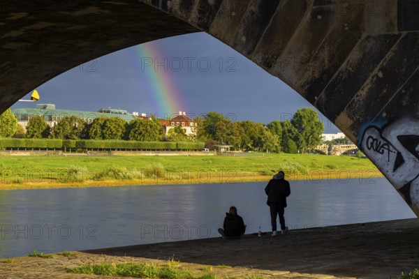Young couple watching the rainbow over the Elbe at Neustädter Elbufer, Dresden, Saxony, Germany