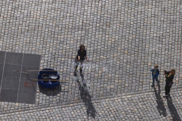 View from the lantern of the Church of Our Lady to the Neumarkt with street artist who delights tourists with soap bubble art, Dresden, Saxony, Germany