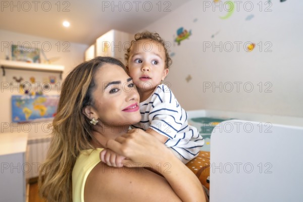 Loving mother cradling her baby son in his cozy bedroom, cherishing a sweet moment filled with warmth and affection