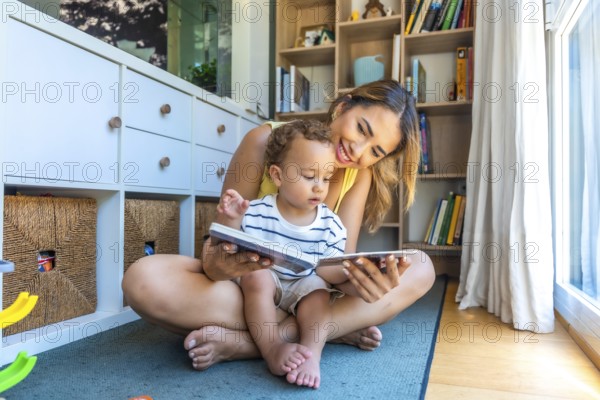 Smiling mother and baby son sharing joyful moments while reading books together, fostering a love for literacy in their cozy playroom