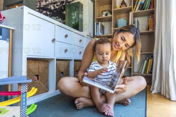 Happy mother and baby son sharing a joyful moment while reading a book together, creating lasting memories in their cozy living room
