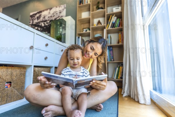 Happy mother and son enjoying quality time together, reading a book on the floor of their cozy living room filled with natural light