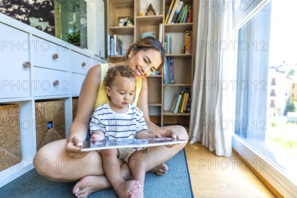 Happy mother and son enjoying quality time together, sitting on the living room floor, engrossed in a book and sharing smiles