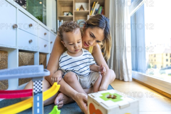 Mom and her son are sitting on the floor enjoying playtime with colorful educational toys, promoting early childhood development and quality time together
