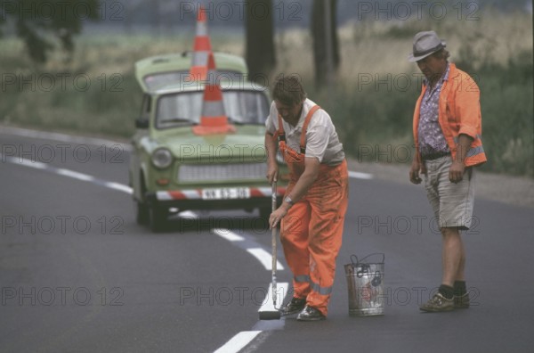 DEU, Erfurt, 01.07.1990 -- Road marking work with duty trombi outside Erfurt. -- Road workers on a street near Erfurt.