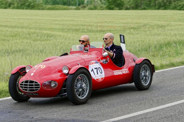 A classic red car with two people driving on a country road, classic car, car race, Mille Miglia, 1000 Miglia, 2015, Tuscany, Rome Lake Garda, Italy
