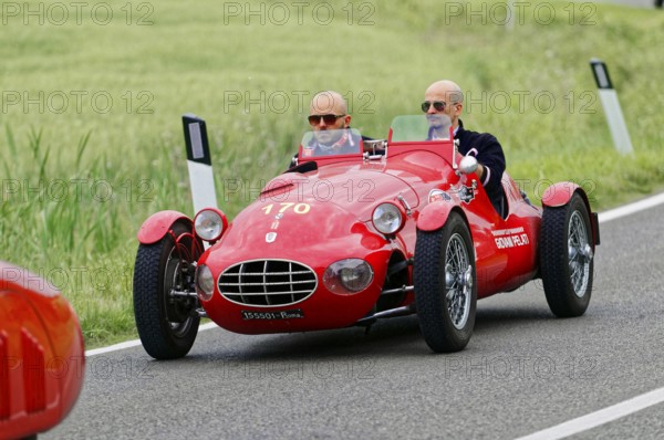 A red sports car with two drivers drives on a rural route, classic car, car race, Mille Miglia, 1000 Miglia, 2015, Tuscany, Rome Lake Garda, Italy