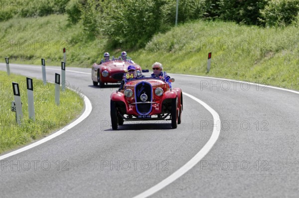 Red classic car in a sharp bend, followed by other classic cars on a country road, classic car, car race, Mille Miglia, 1000 Miglia, 2015, Tuscany, Rome Lake Garda, Italy