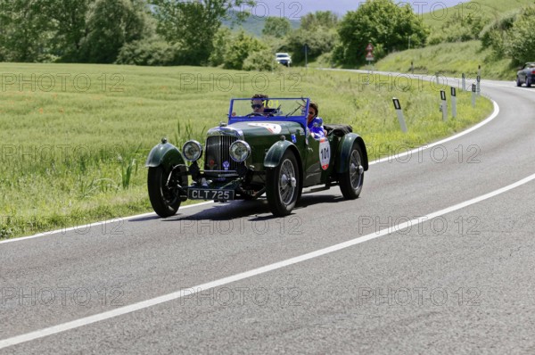 Green classic car drives on a winding country road through a green landscape, classic car, car race, Mille Miglia, 1000 Miglia, 2015, Tuscany, Rome Lake Garda, Italy