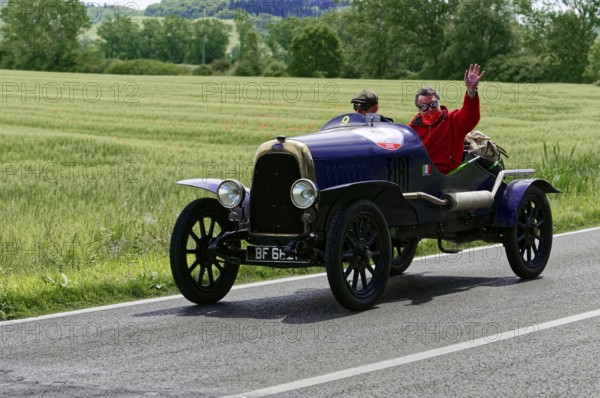 Black vintage car with two men, one waving, on road landscape in spring, vintage car, car race, Mille Miglia, 1000 Miglia, 2015, Tuscany, Rome Lake Garda, Italy