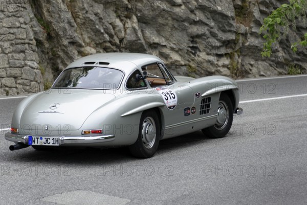 No.315, Merdedes-Benz 300SL W 198, year 1954, Silver classic car driving on a road with rocks in the background, Mille Miglia 2014 or 1000 Miglia, vintage car race, San Marino, Italy
